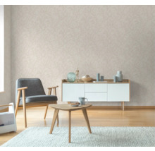 Vardagsrum med fåtölj, bord, byrå och mönstrad tapet