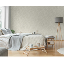 Ljust sovrum med mönstrad tapet, säng, lampa och sidobord