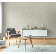 Vardagsrum med beige tapet med bladmönster, fåtölj, byrå och bord