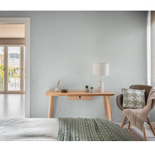 Ljust sovrum med träbord, lampa och stol.