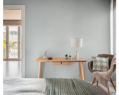 Ljust sovrum med träbord, lampa och stol.