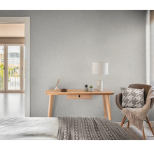 Sovrum med mönstrad tapet, skrivbord, stol och säng