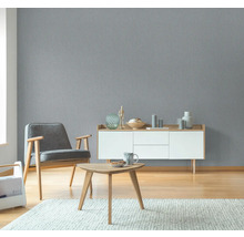 Vardagsrum med grå strukturtapet, fåtölj, byrå och bord