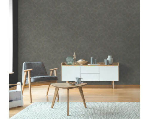 Vardagsrum med fåtölj, sidobord och byrå framför en strukturerad väggtapet.