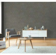 Vardagsrum med grå mönstrad tapet, fåtölj, skänk och bord på matta