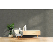 Vardagsrum med grå strukturvägg, fåtölj, växt och byrå