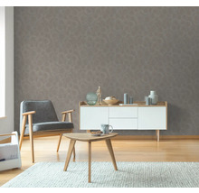 Vardagsrum med grå mönstrad tapet, fåtölj, sidobord och byrå.