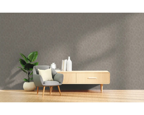 Vardagsrum med grå mönstrad tapet, fåtölj, växt och skänk.