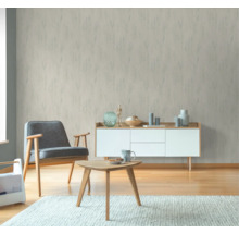 Vardagsrum med mönstrad tapet, fåtölj, bord och byrå