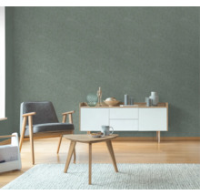 Vardagsrum med grön strukturtapet, fåtölj, bord och skänk