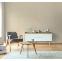 Vardagsrum med fåtölj, soffbord och skänk framför en mönstrad tapet