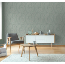 Vardagsrum med tapet med bladmönster, fåtölj, byrå och bord på matta