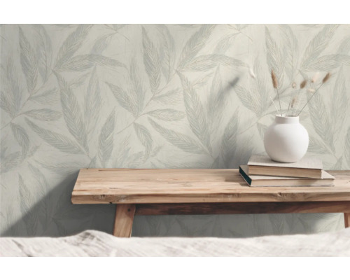 Scen med en tapet med bladmönster, en träbänk, böcker och en vas med dekoration.