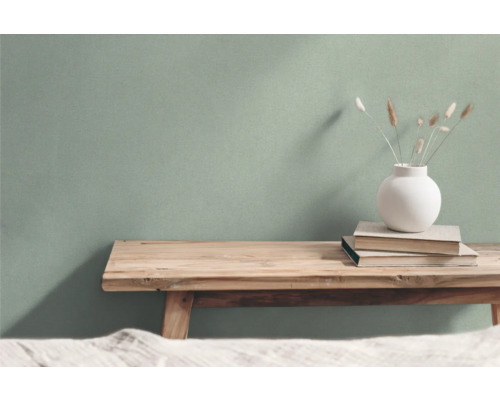 Vardagsrum med träbänk, böcker och vas framför en vägg