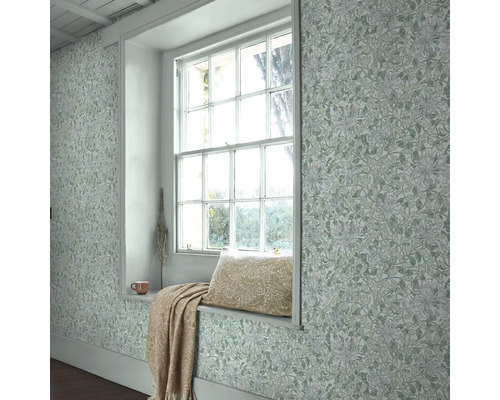 Ljust rum med fönsterbräda, kudde, filt och blommig tapet