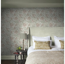 Sovrum med blommig tapet, säng, sängbord och lampa