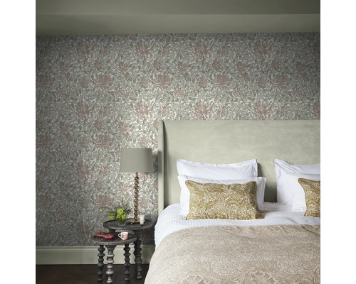 Sovrum med blommig tapet, säng, sängbord och lampa