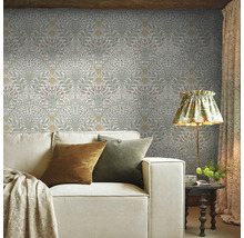 Vardagsrum med blommig tapet, soffa, lampa och sidobord