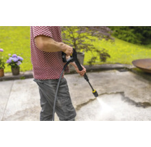 En person använder en högtryckstvätt för att rengöra en terrass.