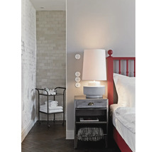 Sovrum med säng, sänglampa, sängbord och serveringsvagn med handdukar