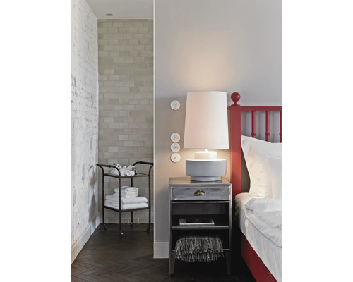 Sovrum med säng, sänglampa, sängbord och serveringsvagn med handdukar