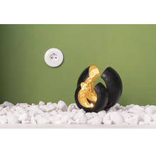 Dekorativ kula med ljus på vita stenar bredvid ett eluttag