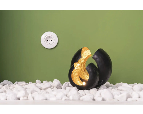 Dekorativ kula med ljus på vita stenar bredvid ett eluttag