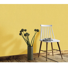 Dekorativ vägg med gul tapet, en blombukett i en vas och en stol.