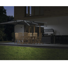 Upplyst trädgårdssittplats med parasoll, bord, stolar och grill