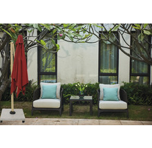 Trädgårdsscen med stängt parasoll, två fåtöljer med kuddar och ett sidobord med en blomvas.