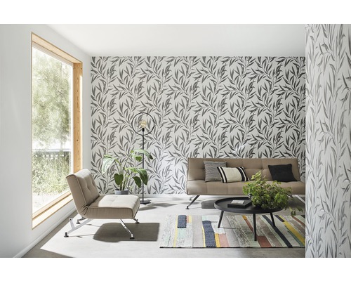 Vardagsrum med blommig tapet, fåtölj, soffa, bord och matta.