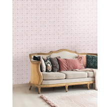 Dekorativt vardagsrum med en soffa och en mönstrad tapet med kronor och bokstäver.