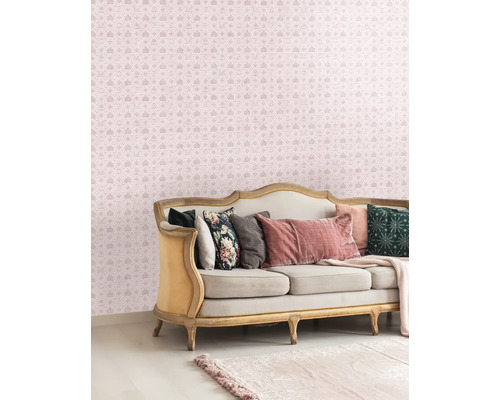 Dekorativt vardagsrum med en soffa och en mönstrad tapet med kronor och bokstäver.