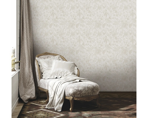 Miljöbild med beige blommig tapet, schäslong med kuddar och filt samt gardin