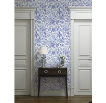 Rumsvy med blåvit mönstrad tapet, byrå, lampa och dörrkarmar