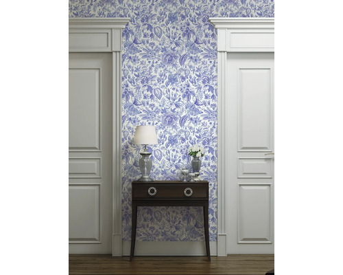 Rumsvy med blåvit mönstrad tapet, byrå, lampa och dörrkarmar