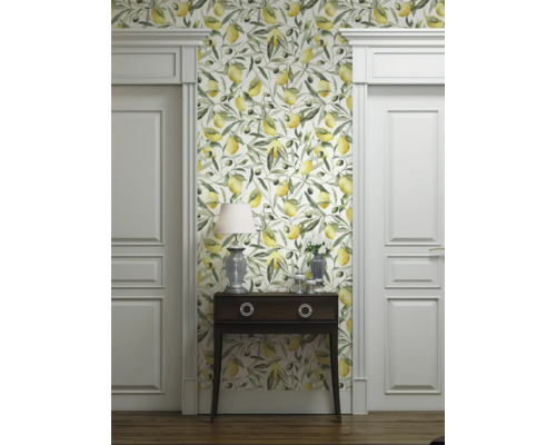 Rumsbild med tapet med citron- och olivmotiv, byrå, lampa och vita dörrar.