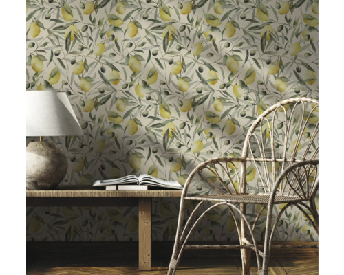 Dekorativt rum med en tapet med citroner och olivkvistar, ett träbord, en lampa, en bok och en rottingstol.