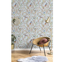 Dekorativt rum med tapet med fågelmönster, fåtölj, golvlampa, spegel, krukväxt och matta