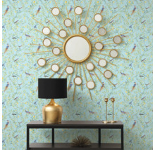 Dekorativ interiör med en rund spegel i form av en sol, en bordslampa och en konsol mot en mönstrad tapet.
