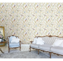 Ljus, vänlig inredning med blommig tapet med fåglar, soffa och fåtölj