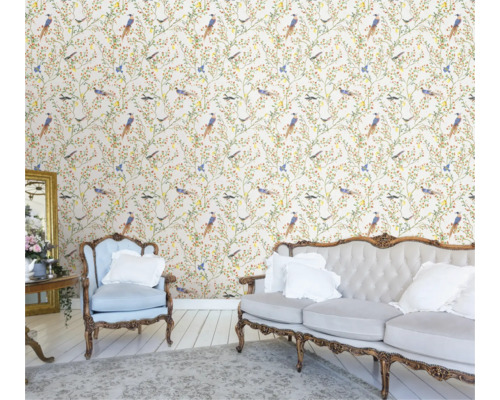 Ljus, vänlig inredning med blommig tapet med fåglar, soffa och fåtölj