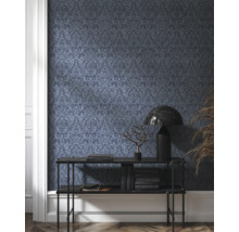 Rumsbild med mörk mönstrad tapet, konsolbord, lampa och dekoration