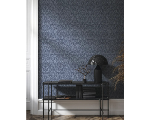 Rumsbild med mörk mönstrad tapet, konsolbord, lampa och dekoration