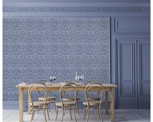 Matsal med utsmyckade tapeter, träbord och stolar.