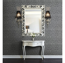 Väggdekoration med mönstrad tapet, spegel med ornamental ram, vägglampor och konsol