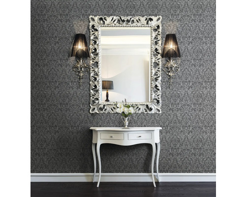 Väggdekoration med mönstrad tapet, spegel med ornamental ram, vägglampor och konsol