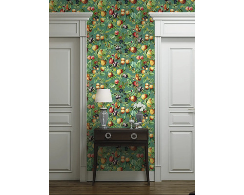 Dekorativt rum med en grön tapet med fruktmönster, flankerad av två vita dörrar och ett mörkt träskåp.