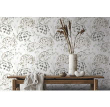 Dekorativ tapet med blommönster på vit bakgrund, tillsammans med ett träbord med dekorationer och en duk