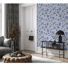 Vardagsrum med blommönstrad tapet, soffa, pall och dekorationer för en mysig atmosfär